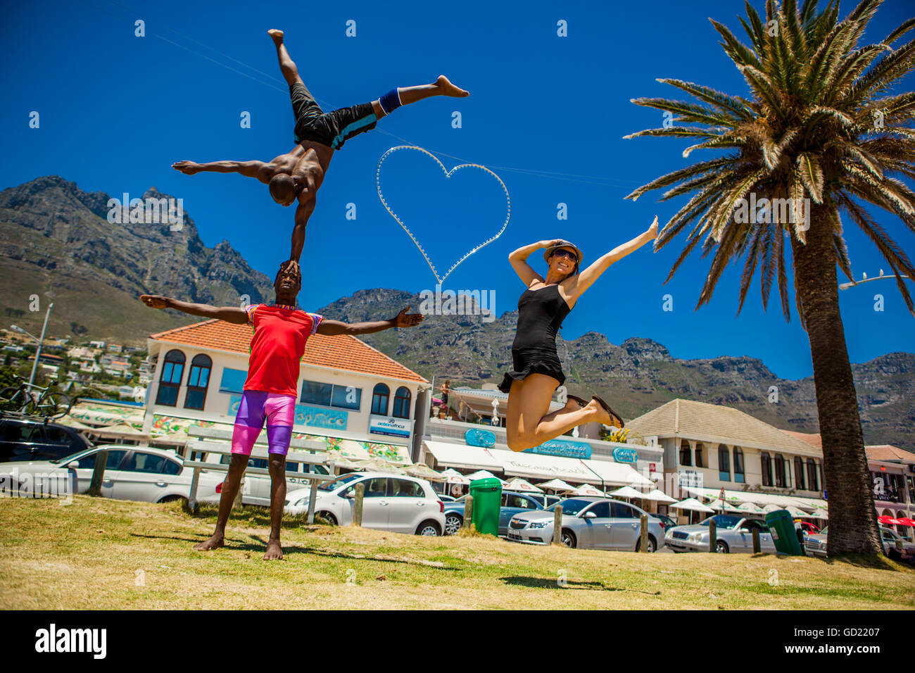 Laura Grier springen mit afrikanischen Akrobaten, Camps Bay, Südafrika, Afrika Stockfoto