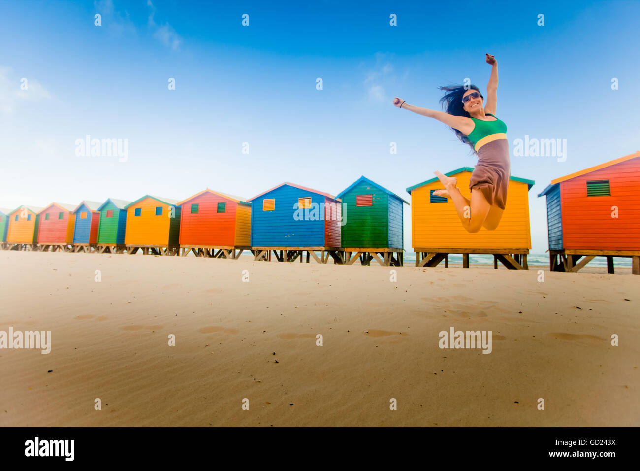 Laura Grier springen vor bunten Strand Hütten, Muizenberg Beach, Cape Town, Südafrika, Afrika Stockfoto