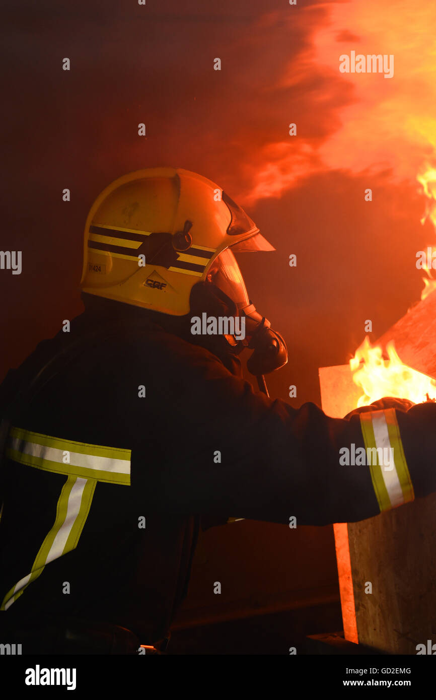 Feuerwehr. VEREINIGTES KÖNIGREICH. Great Britain. Feuerwehrmann befasst sich eine Flamme Stockfoto
