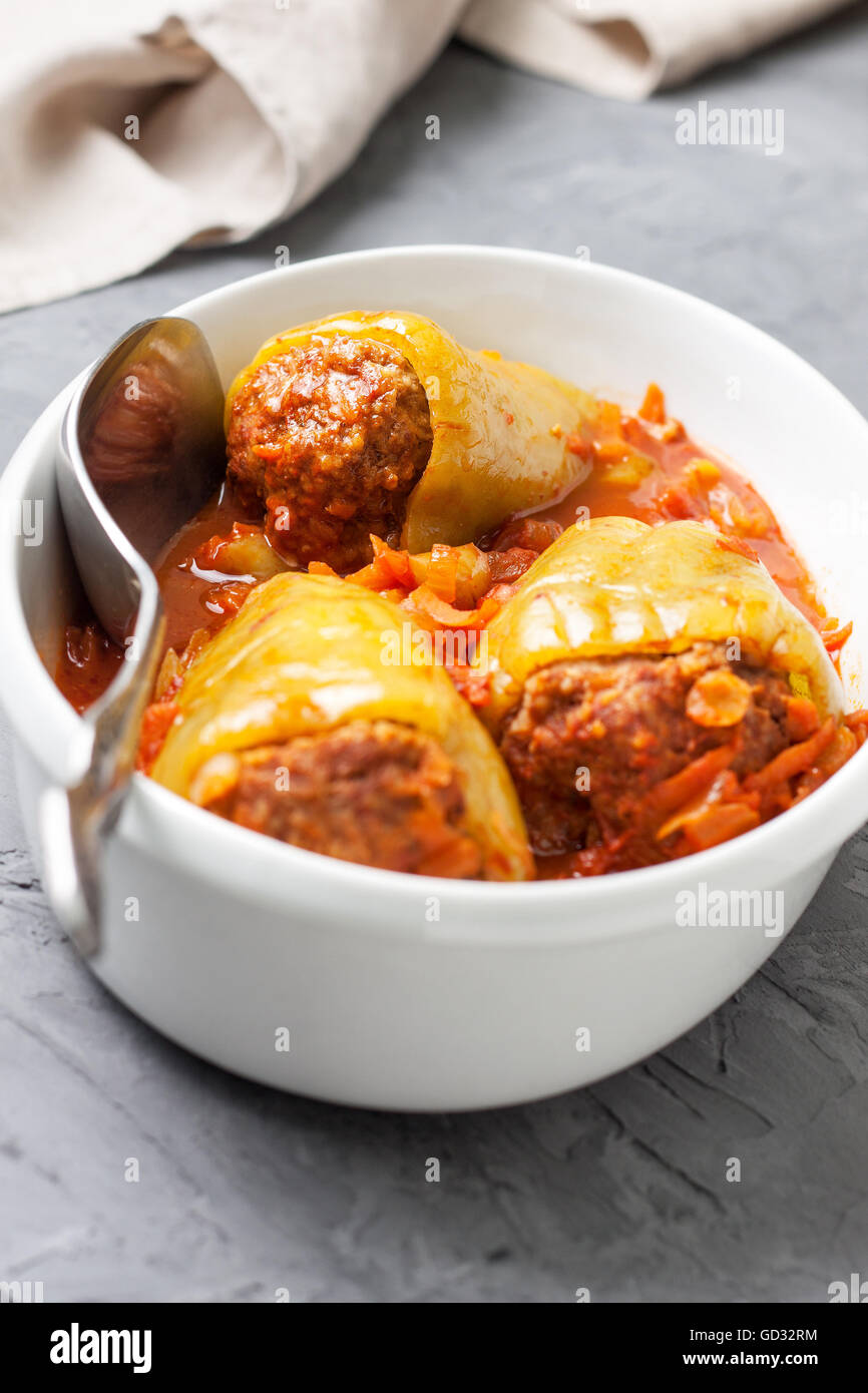 Paprika gefüllt mit Tomatensauce in einem weißen Teller zum Braten auf einem konkreten Hintergrund Stockfoto