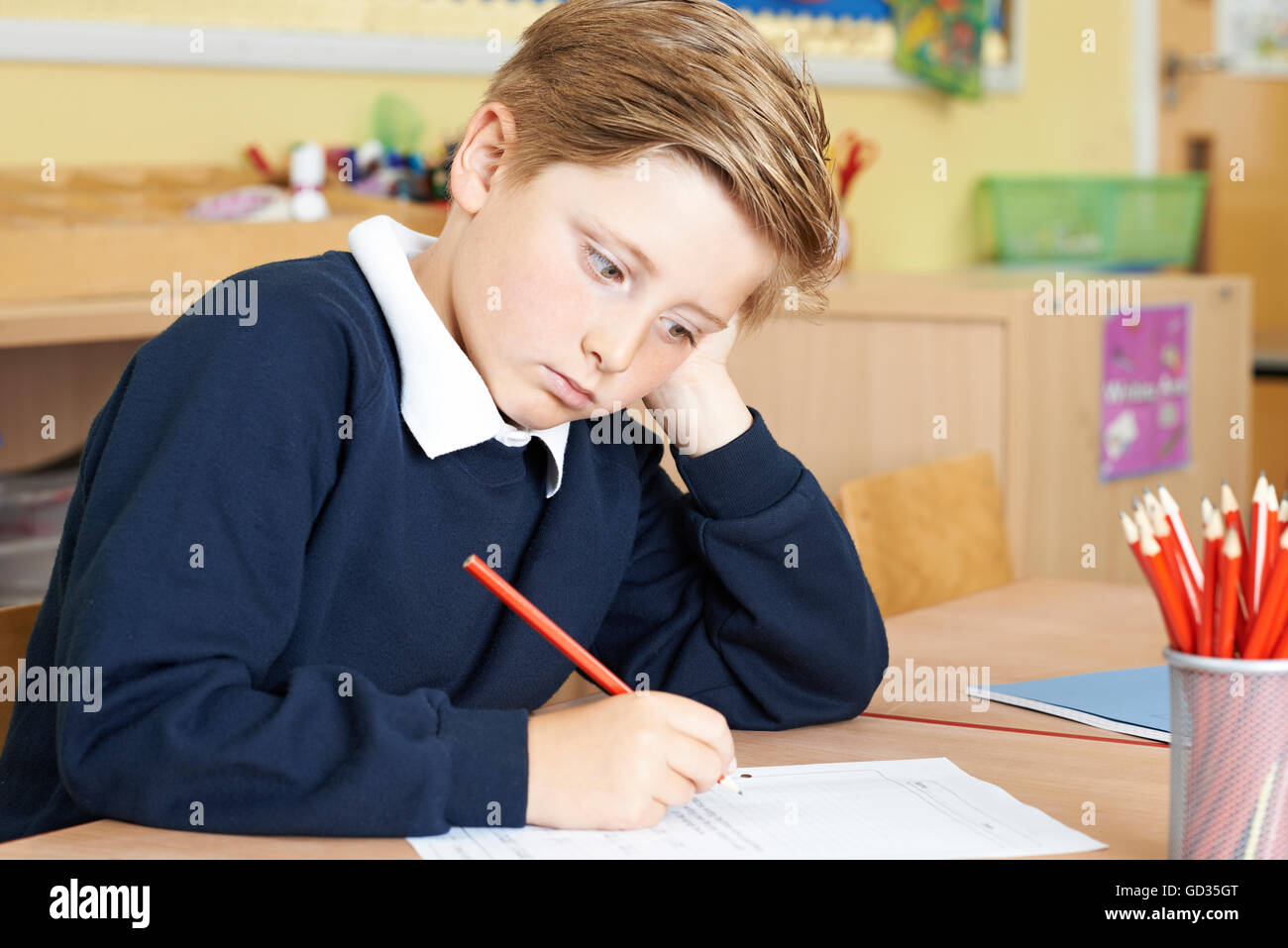 Gelangweilt männlichen Grundschule Schüler am Schreibtisch Stockfoto