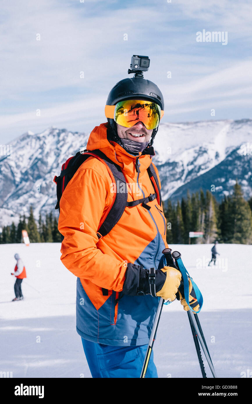 Ein Mann in orange Skijacke mit einem Kopf Cam und Helm. Stockfoto