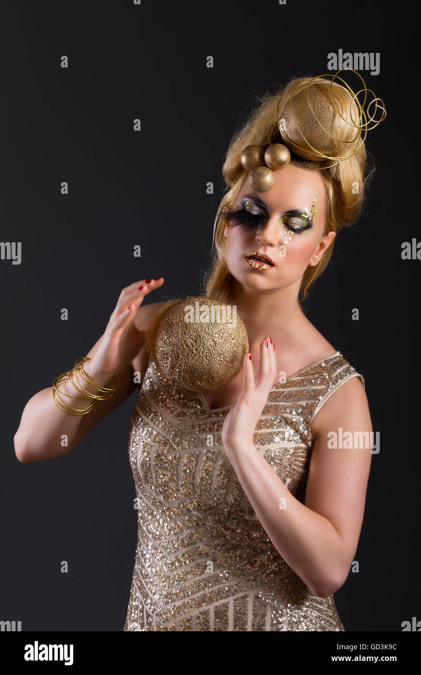 Blonde Avantgarde kreative Make-up, gold Kugeln, Glitter Paillettenkleid, roten Hintergrund, Blattgold, architektonische Haar, Kopfbedeckung Stockfoto