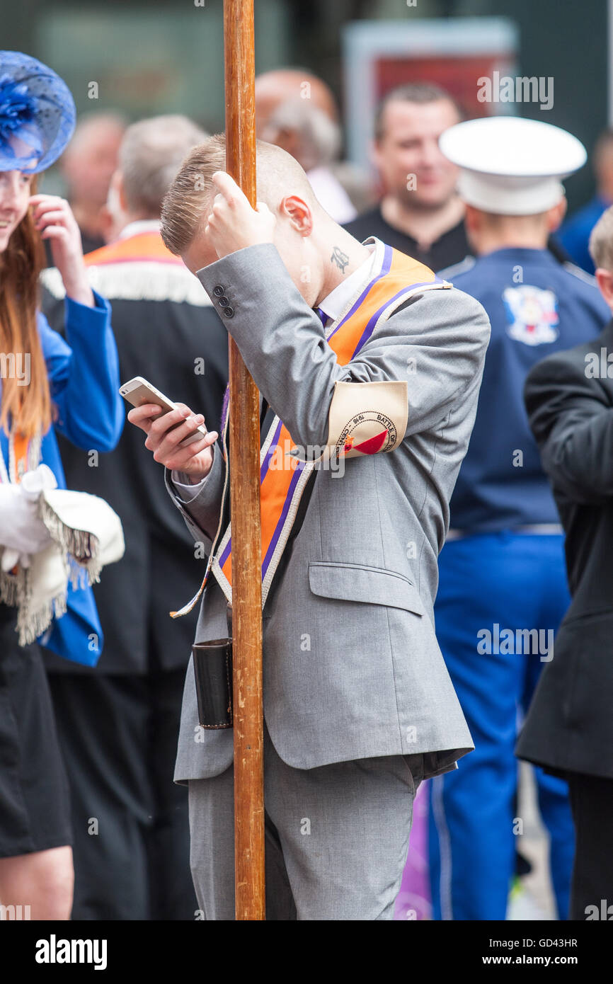 Belfast, UK. 12. Juli 2016. Ein Mann, der sein Handy überprüfen, nachdem der Zug der Demonstranten während der zwölften März beendet. Es entstand während des späten 18. Jahrhunderts in Ulster. Es feiert die Glorious Revolution (1688) und der Sieg des protestantischen Königs Wilhelm von Oranien über katholische König James II an Schlacht des Boyne (1690) Credit: Bonzo/Alamy Live News Stockfoto