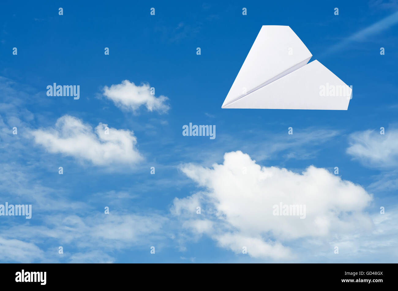 Papierflieger fliegen über den Wolken mit blauem Himmel. Stockfoto