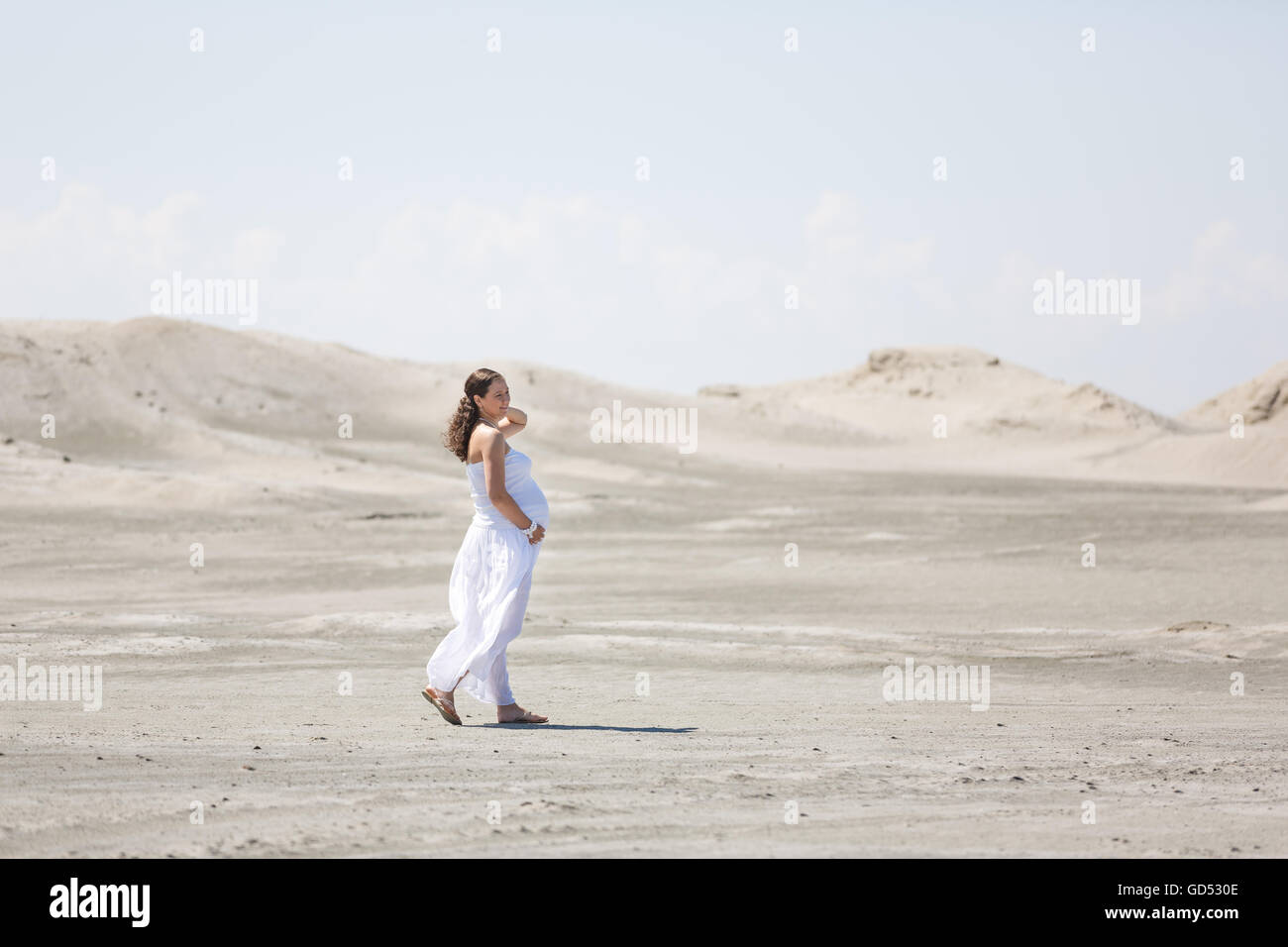 Die schwangere Frau zu Fuß am Strand im Sommer Stockfoto