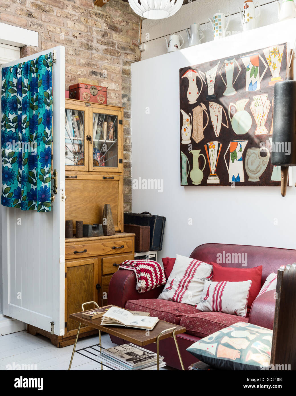 Jo Oakley Malerei "Schiffe" über eine Ledercouch im Wohnzimmer mit hölzernen Schrank und Retro-print Vorhang hing Stockfoto