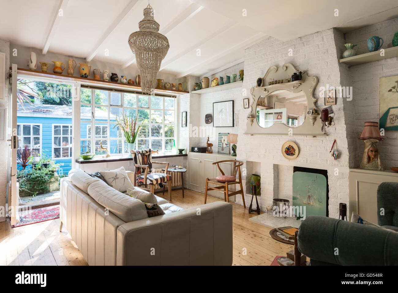 Helle und luftige Wohnzimmer mit Kaminsims Spiegel, Hans Wegner "Wishbone" Stuhl und dekorative Keramik, die auf einem hohen Regal angezeigt Stockfoto