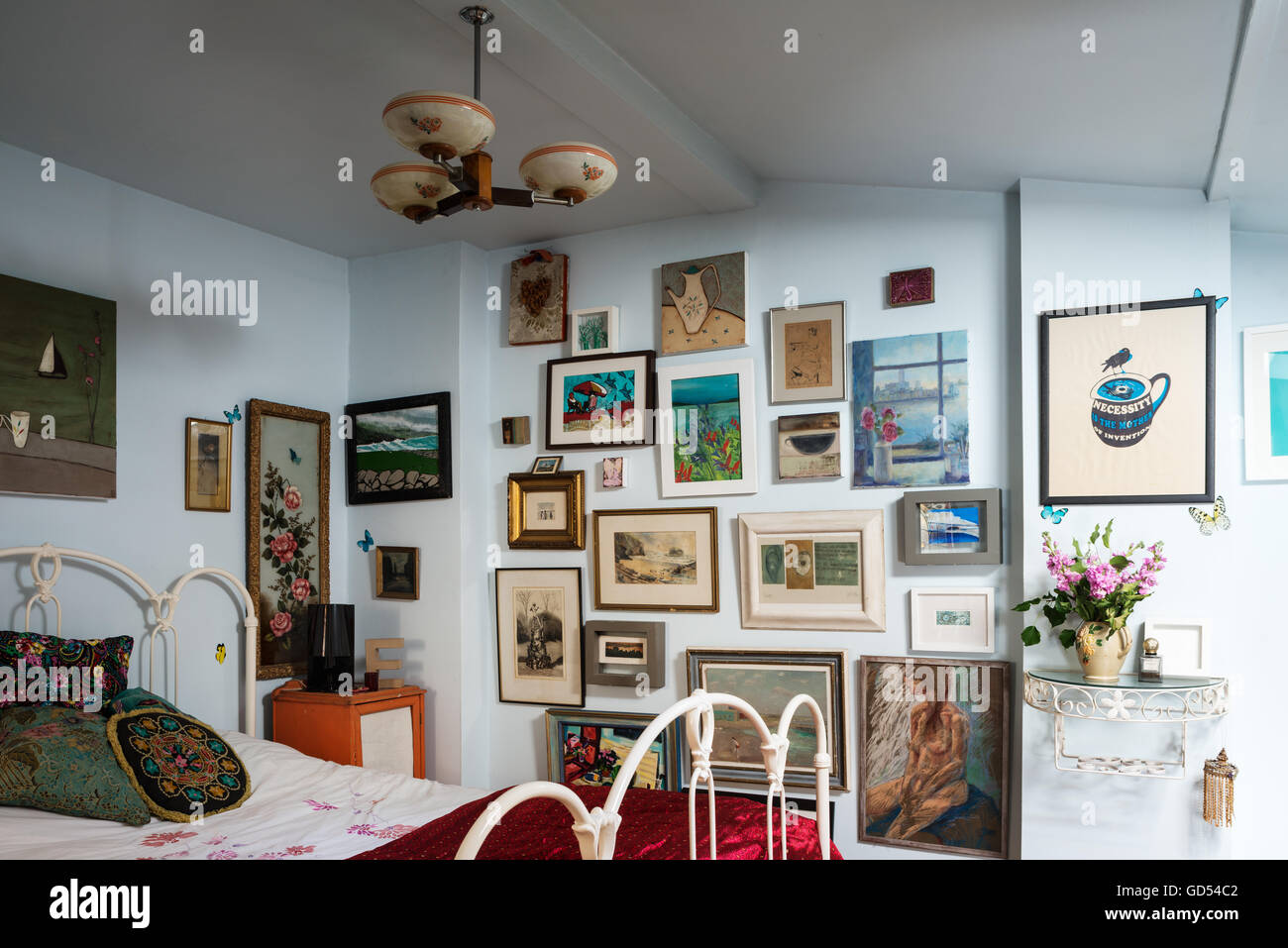 Verschiedene Kunstwerke auf der Wand des Schlafzimmers mit eisernen Bettgestell Stockfoto