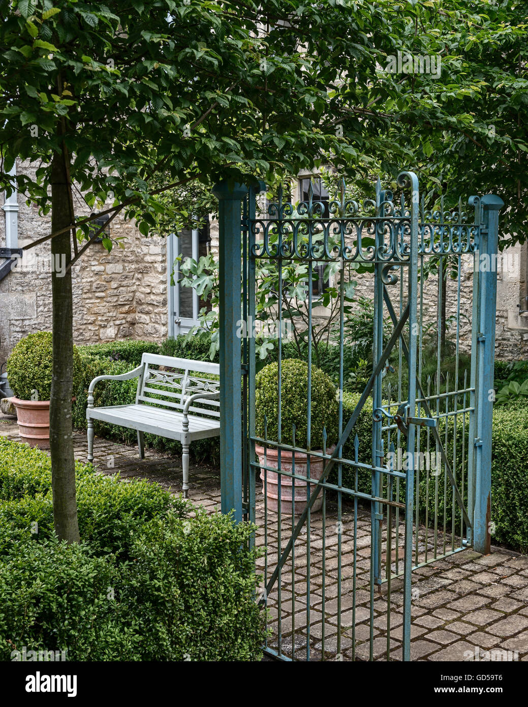 Blaue schmiedeeisernen Tore Garten Eingang mit gepflasterten Weg, Box Hecke und Holzbank Stockfoto