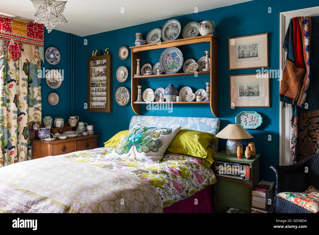 Poole Pottery angezeigt auf hölzernen Regal im Schlafzimmer gemalt in Blue Deep Space von kleinen Greene.The Bett gepolstert ist und bedeckten Stockfoto