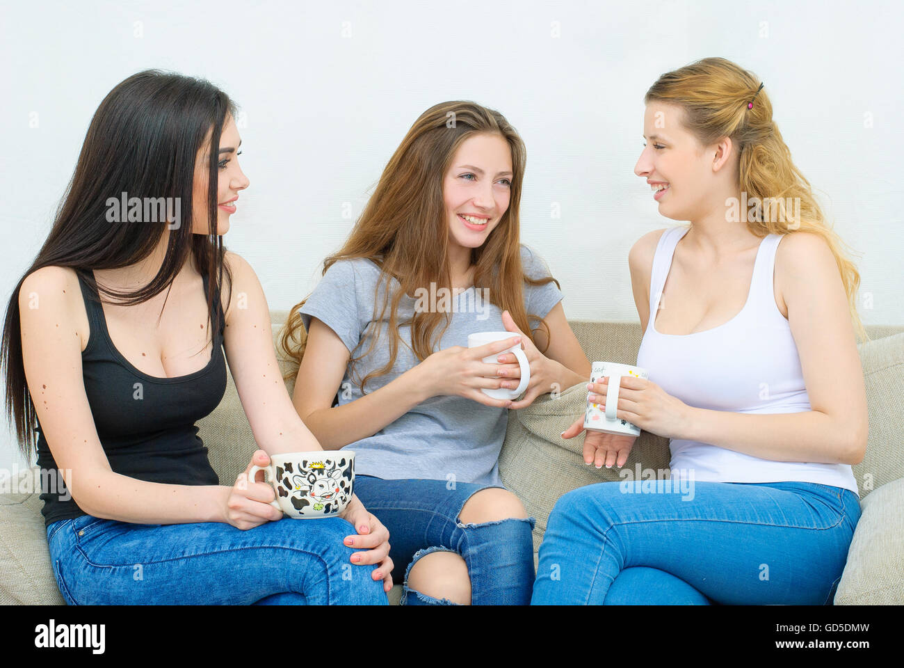 Drei glückliche Freunde reden und trinken Kaffee oder Tee Stockfoto