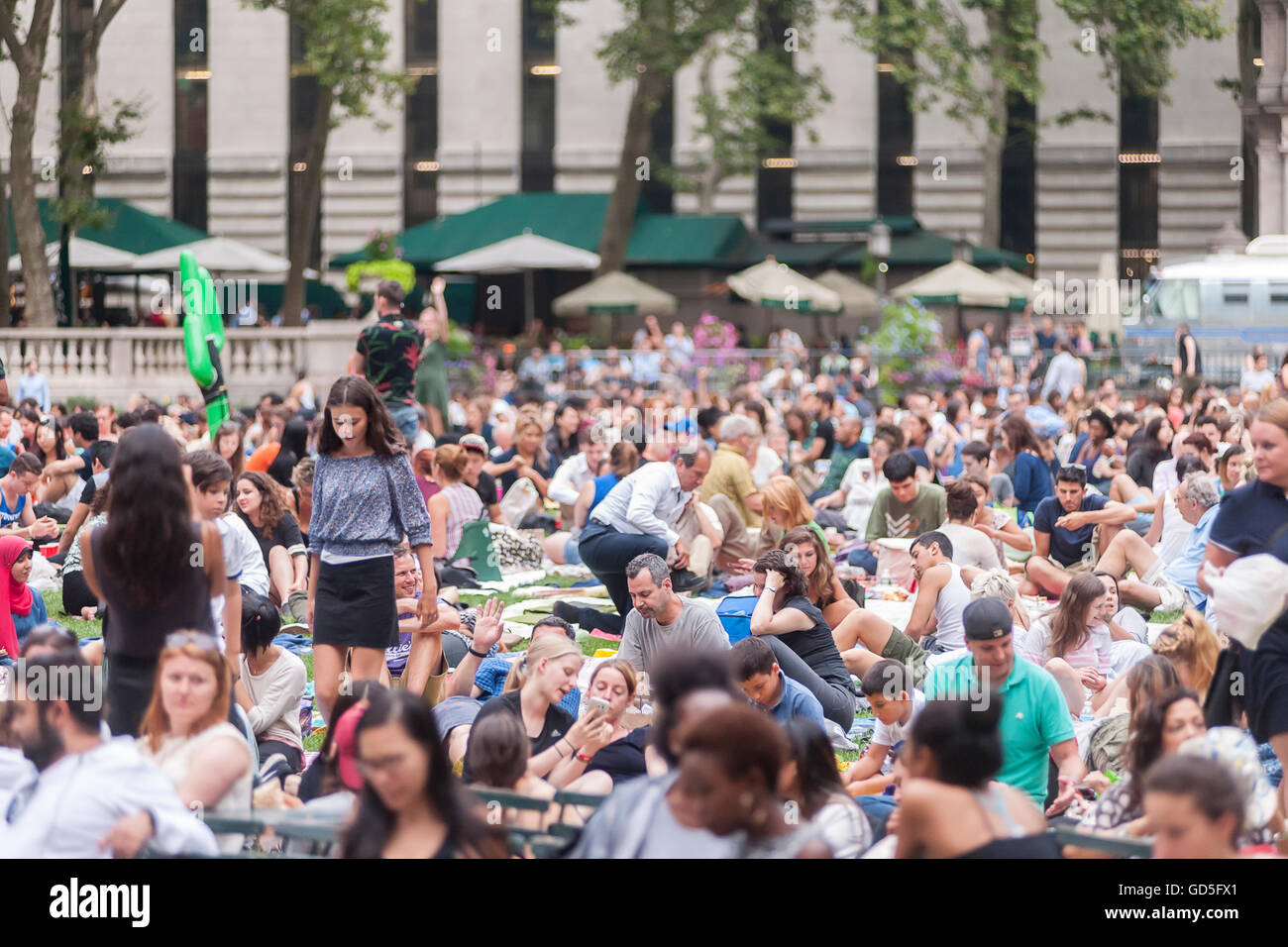 Tausende von Menschen ihre decken zu verbreiten und behaupten, ihre Plätze im Bryant Park in New York auf Montag, 11. Juli 2016 für die HBO Bryant Park Summer Film Festival. Der Park zeigt Filme am Montagabend während des Sommers zieht eine Vielzahl von Besuchern und bis zu schätzungsweise 8000 Menschen. (© Richard B. Levine) Stockfoto