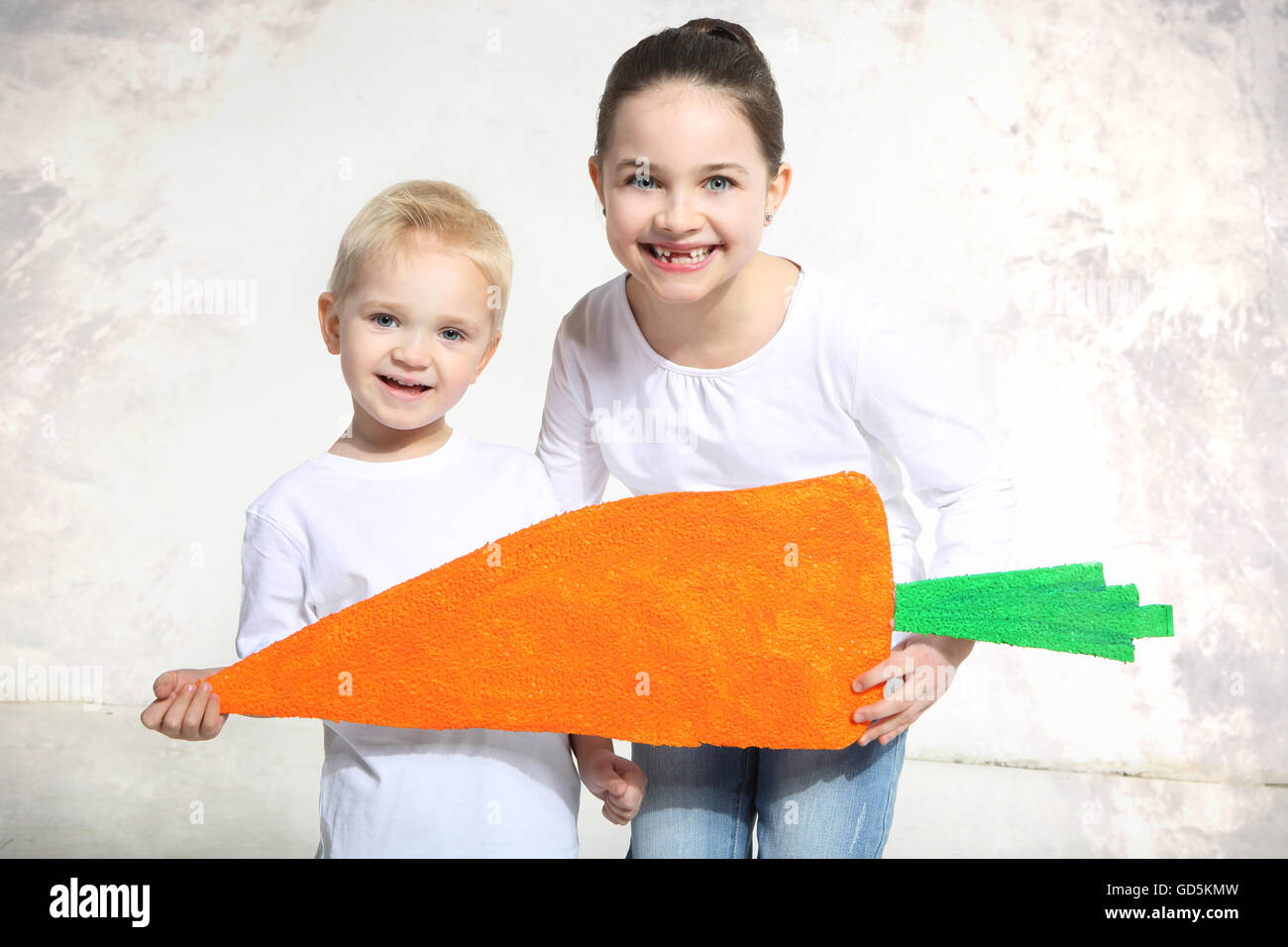 Bruder und Schwester posiert mit bemalten Karotte im studio Stockfoto