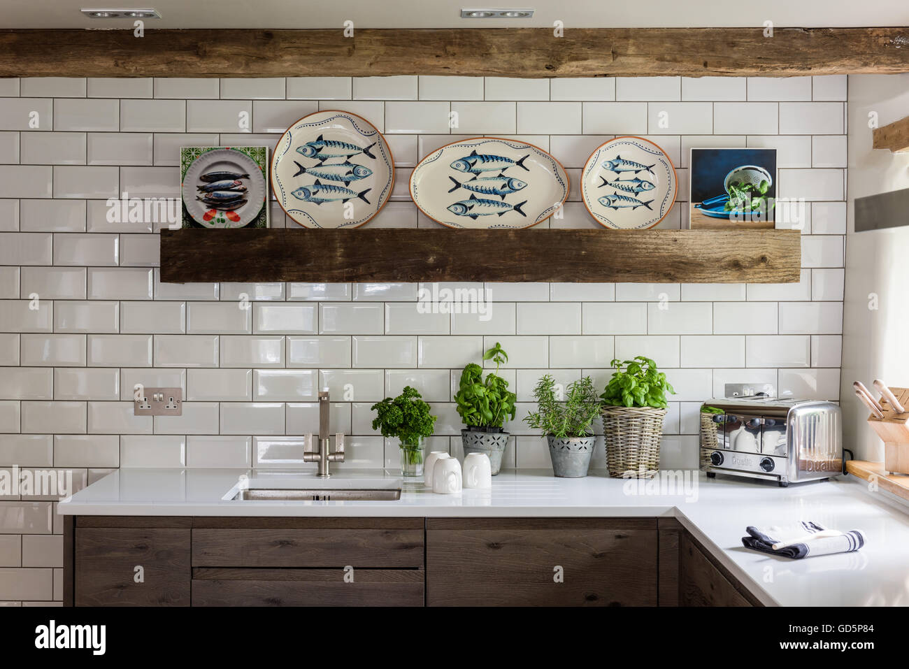 Zierfische-Platten von Wendy Bray in der Küche mit weißen Metro Wandfliesen, Silestone Arbeitsplatten und Holzbalken Stockfoto