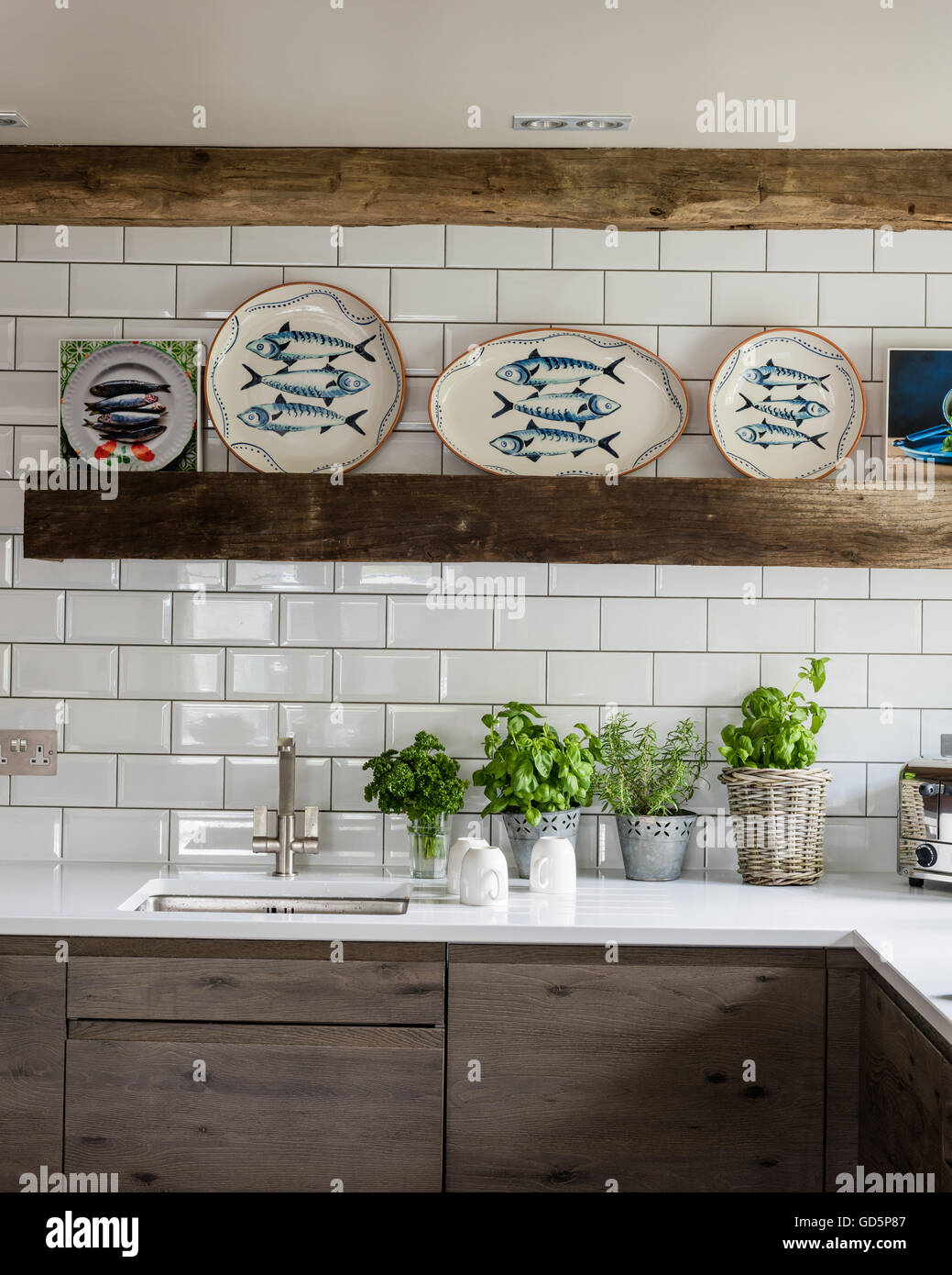 Zierfische-Platten von Wendy Bray in der Küche mit weißen Metro Wandfliesen, Silestone Arbeitsplatten und Holzbalken Stockfoto