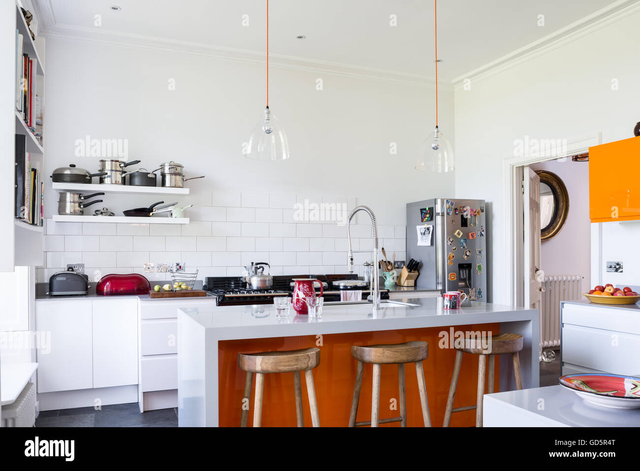 Hölzerne Barhocker in hohen Decken Küche mit weißen Fliesen u. Die Klarglas-Lichtkuppeln sind Baileys Zuhause Stockfoto
