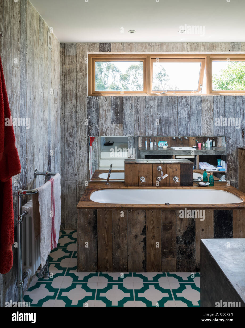 Badewanne, gekleidet in recycelten Dielen im Bad mit Parkett Türkis Vinylfußbodenfliesen von Neisha Crosland Stockfoto