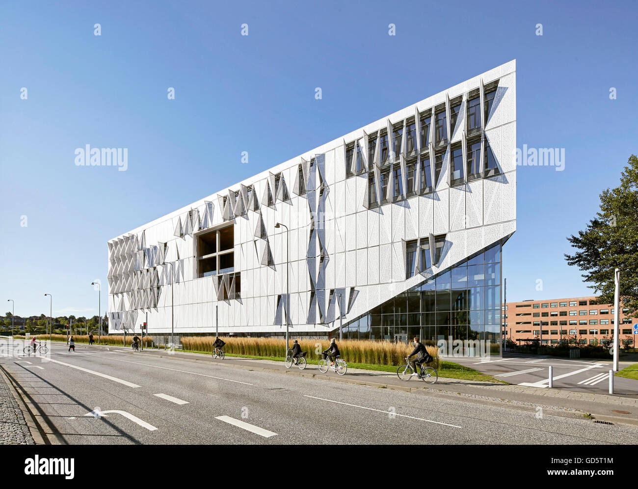 Gebäude-Perspektive mit Straße und Radfahrer. SDU Campus Kolding, Kolding, Dänemark. Architekt: Henning Larsen Architects, 2015. Stockfoto