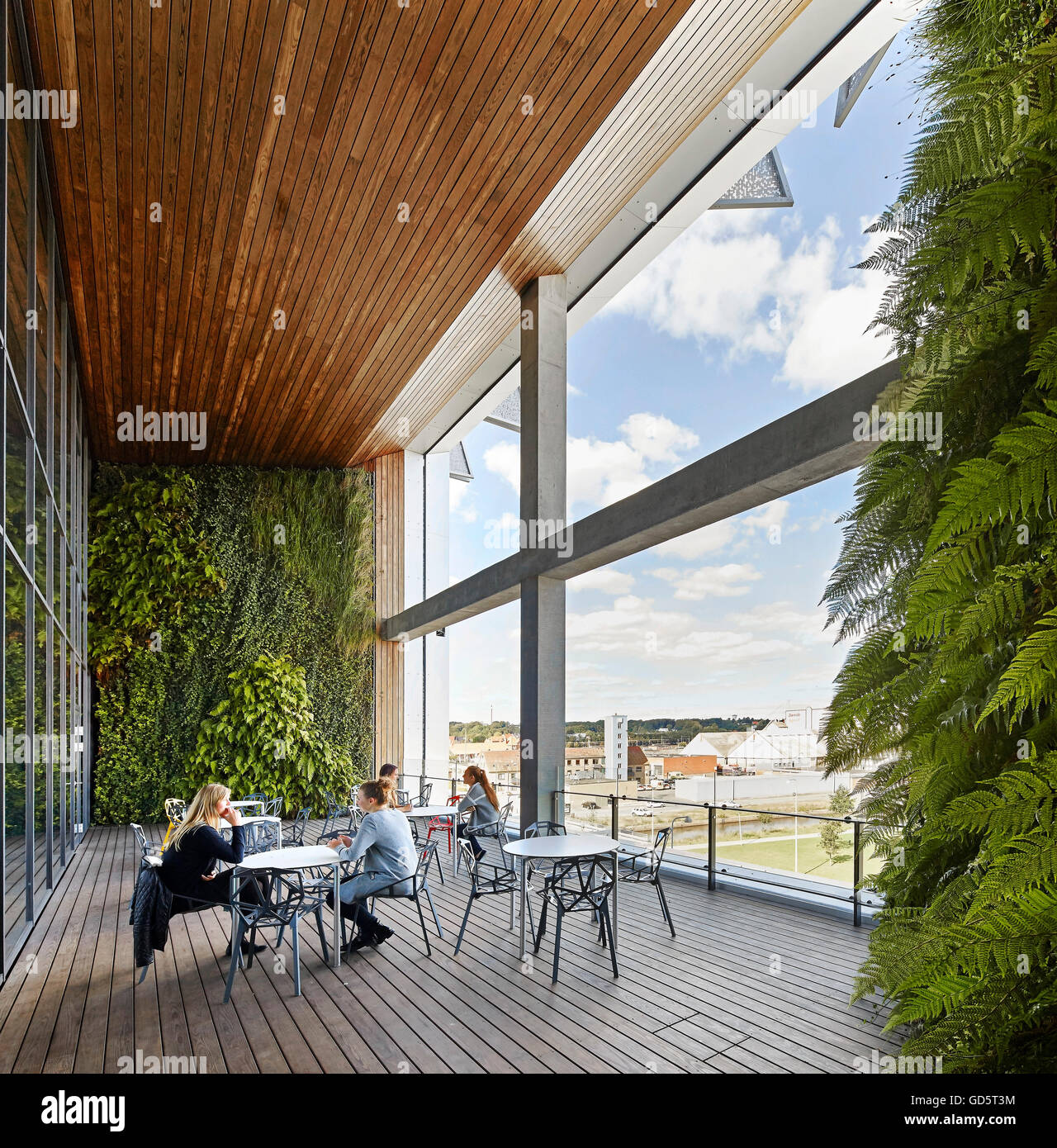 Überdachte und Holz Terrasse mit Sitzgelegenheiten geschmückt. SDU Campus Kolding, Kolding, Dänemark. Architekt: Henning Larsen Architects, 2015. Stockfoto