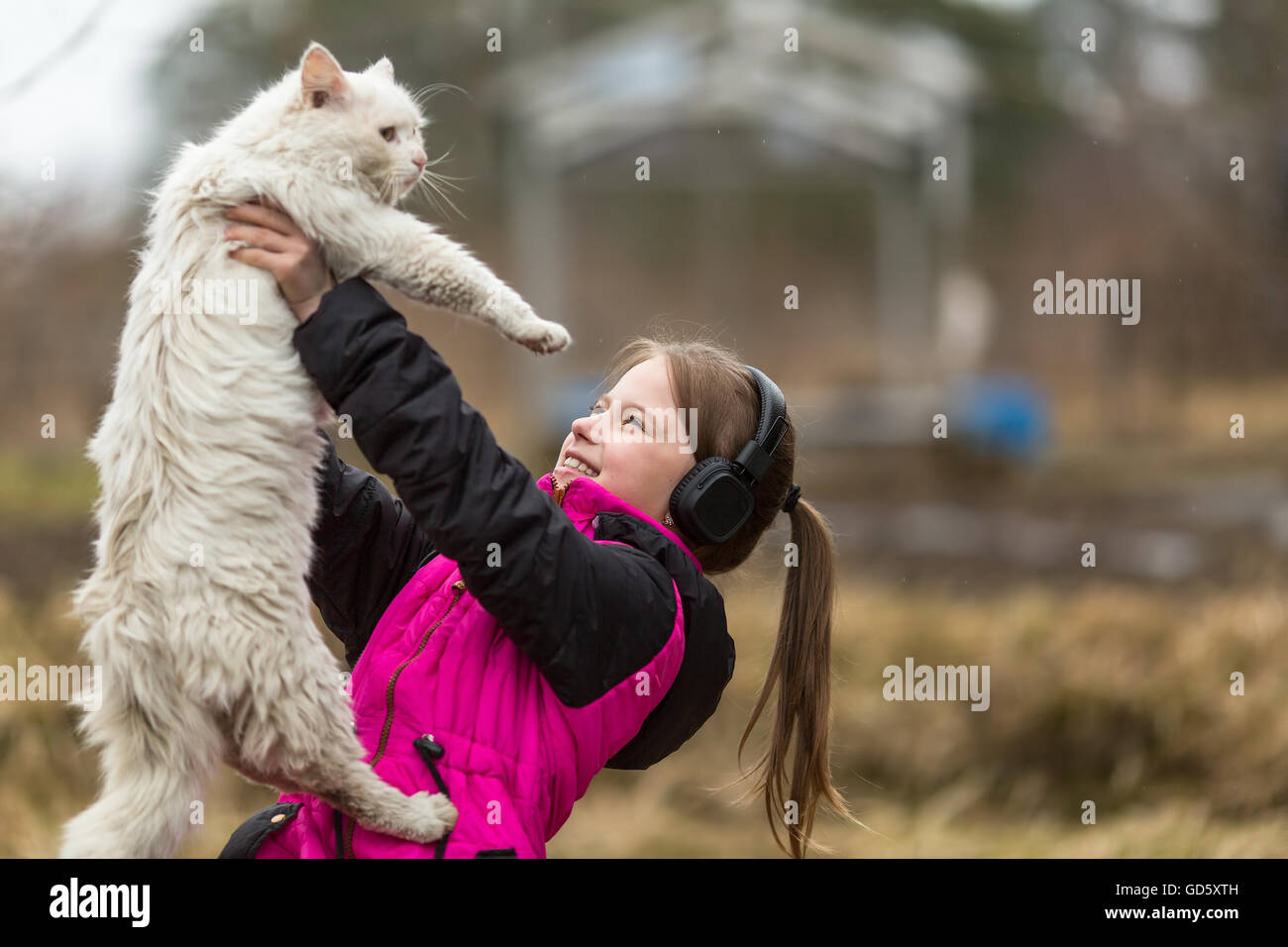 Ein kleines freches Mädchen Kopfhörer spielen mit der Katze. Stockfoto