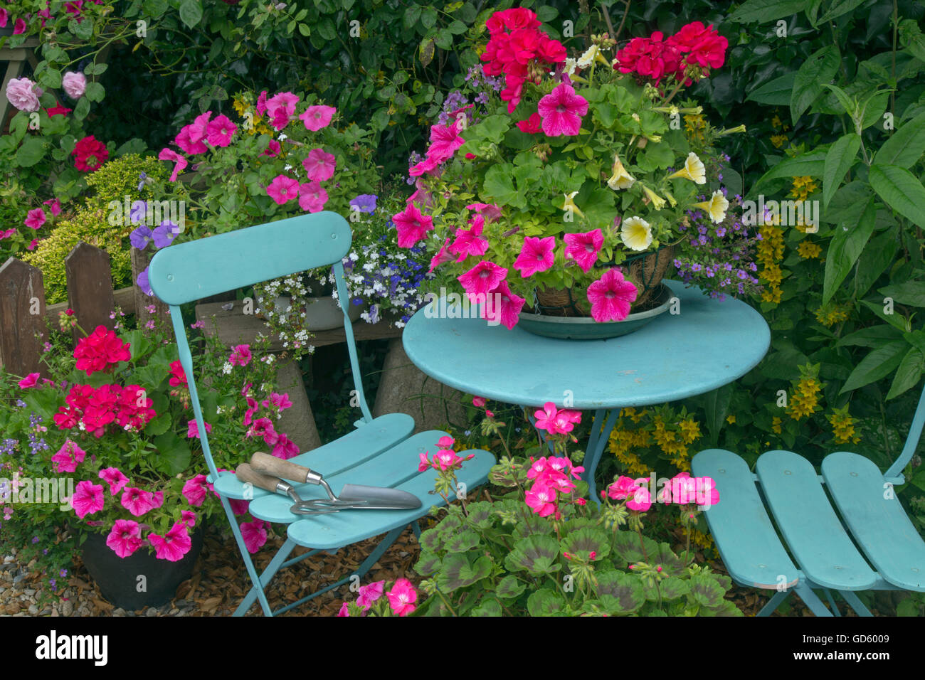 Hübsche Bauerngarten mit Blume Container und blauer Tisch und Stühlen Stockfoto