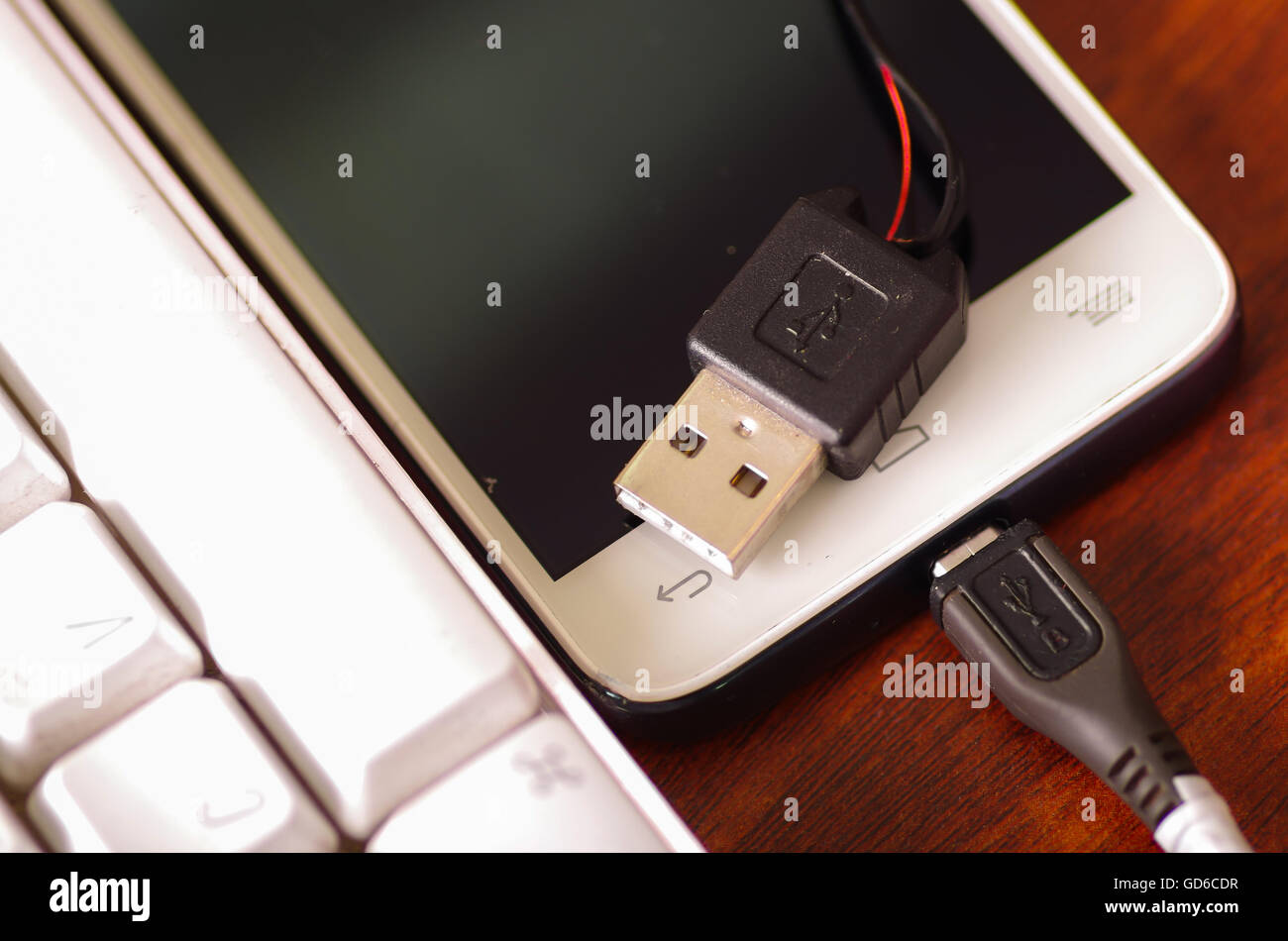 USB-mobiles Ladegerät Kabel angeschlossen in Smartphone liegen auf  Holzoberfläche neben Computer-Tastatur gebrochen, Teil des Drahtes durch  Riss im Kunststoff-Schutz ausgesetzt Stockfotografie - Alamy
