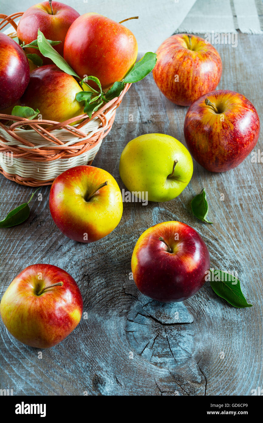 Frische Äpfel im Weidenkorb auf dem rustikalen Hintergrund. Frisches Obst als vegetarisches Essenskonzept. Stockfoto