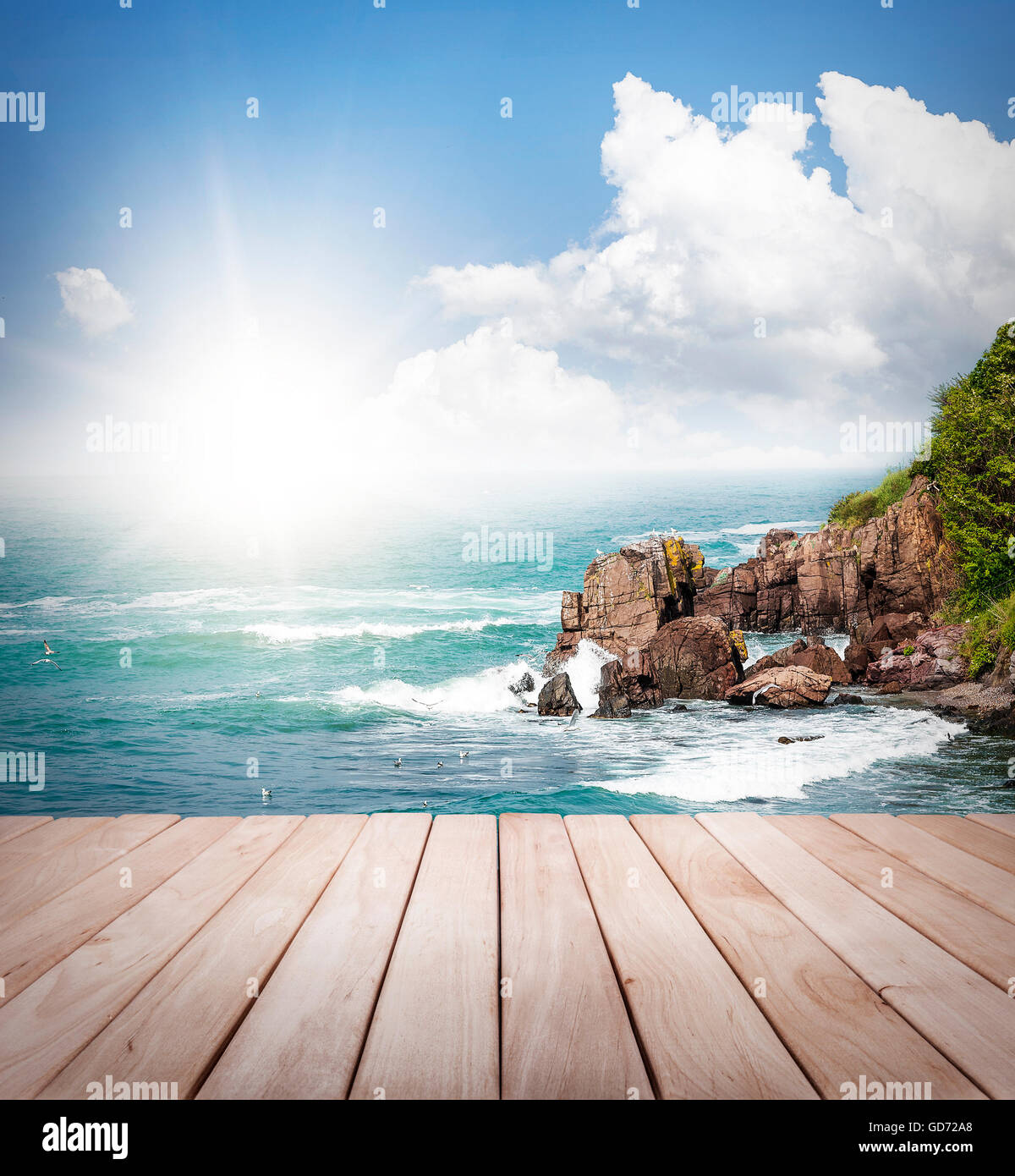 Seelandschaft. Leere Holzplattform und strahlende Sonne auf einem Hintergrund auf das Meer und die felsige Küste. Stockfoto