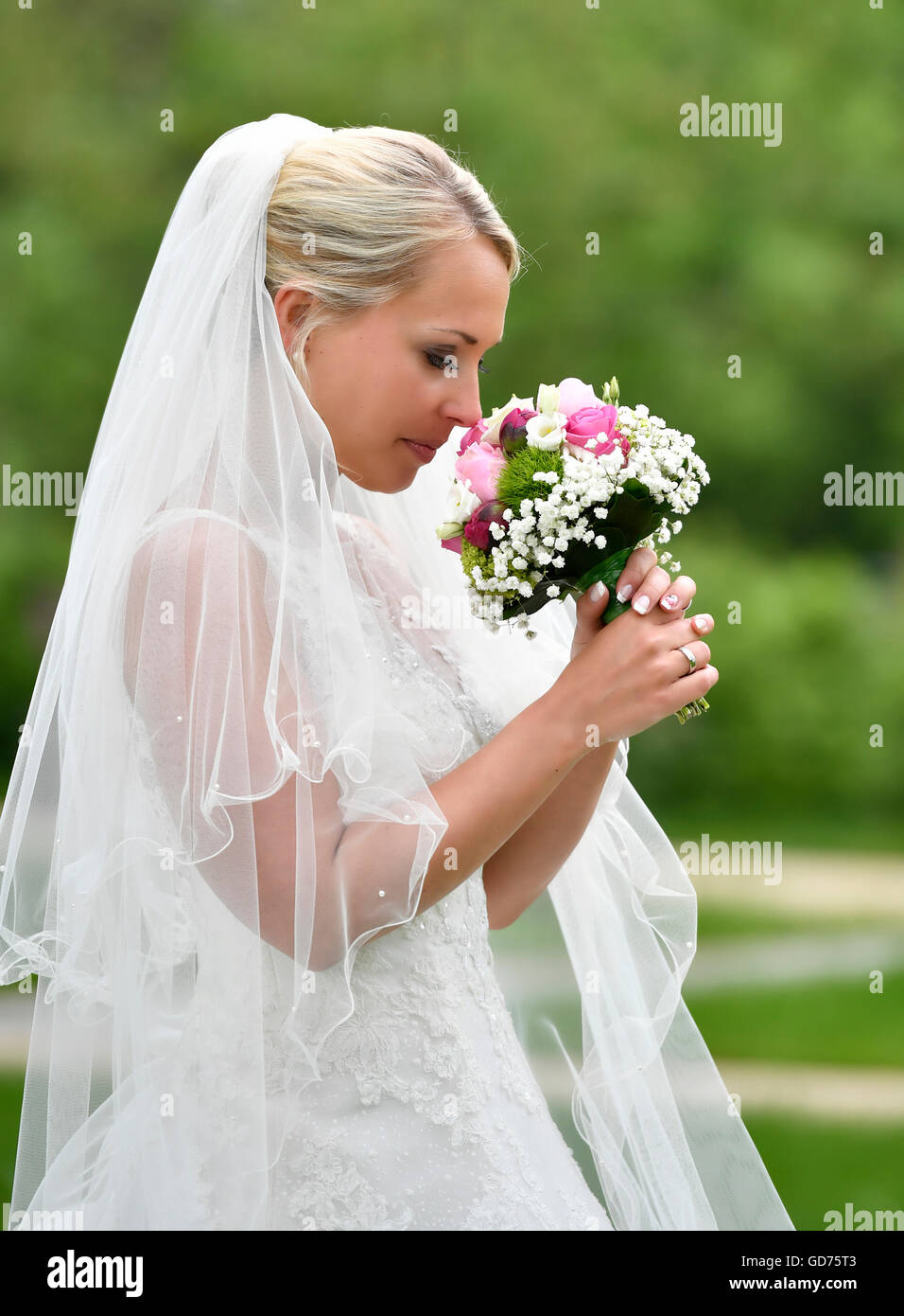 Braut im Hochzeitskleid mit Brautstrauß und Schleier, Deutschland Stockfoto