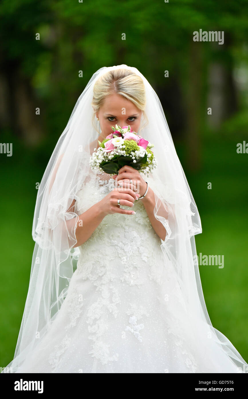 Braut im Brautkleid mit Schleier, riechen Brautstrauß, Deutschland Stockfoto