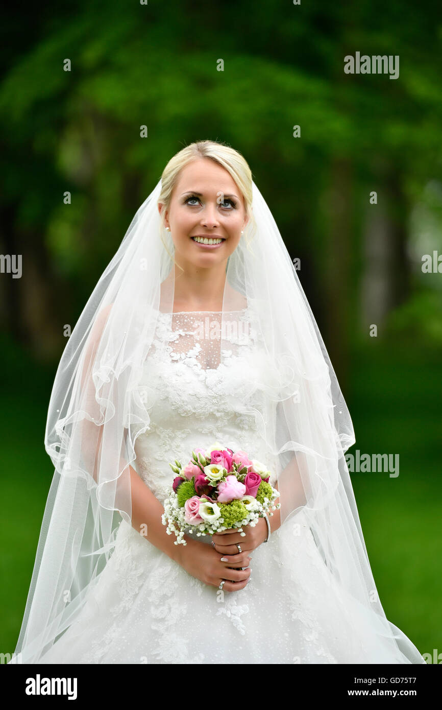 Braut im Hochzeitskleid mit Brautstrauß und Schleier, Deutschland Stockfoto