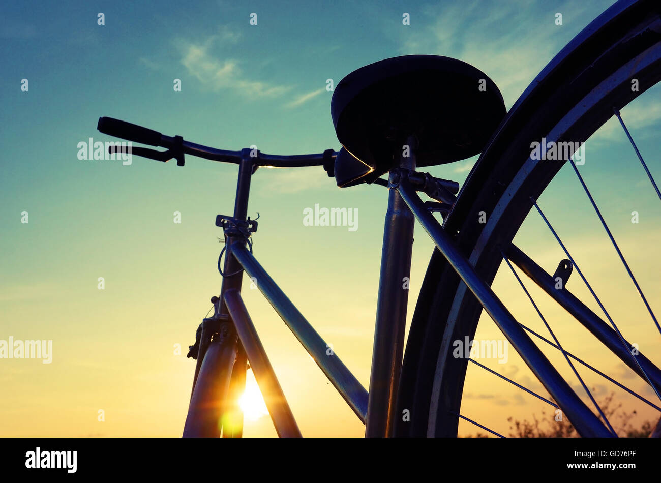 Schöne Nahaufnahme Szene des Fahrrades bei Sonnenuntergang, Sonne am blauen Himmel mit Vintage Farben Silhouette des Rad nach vorne zur Sonne Stockfoto