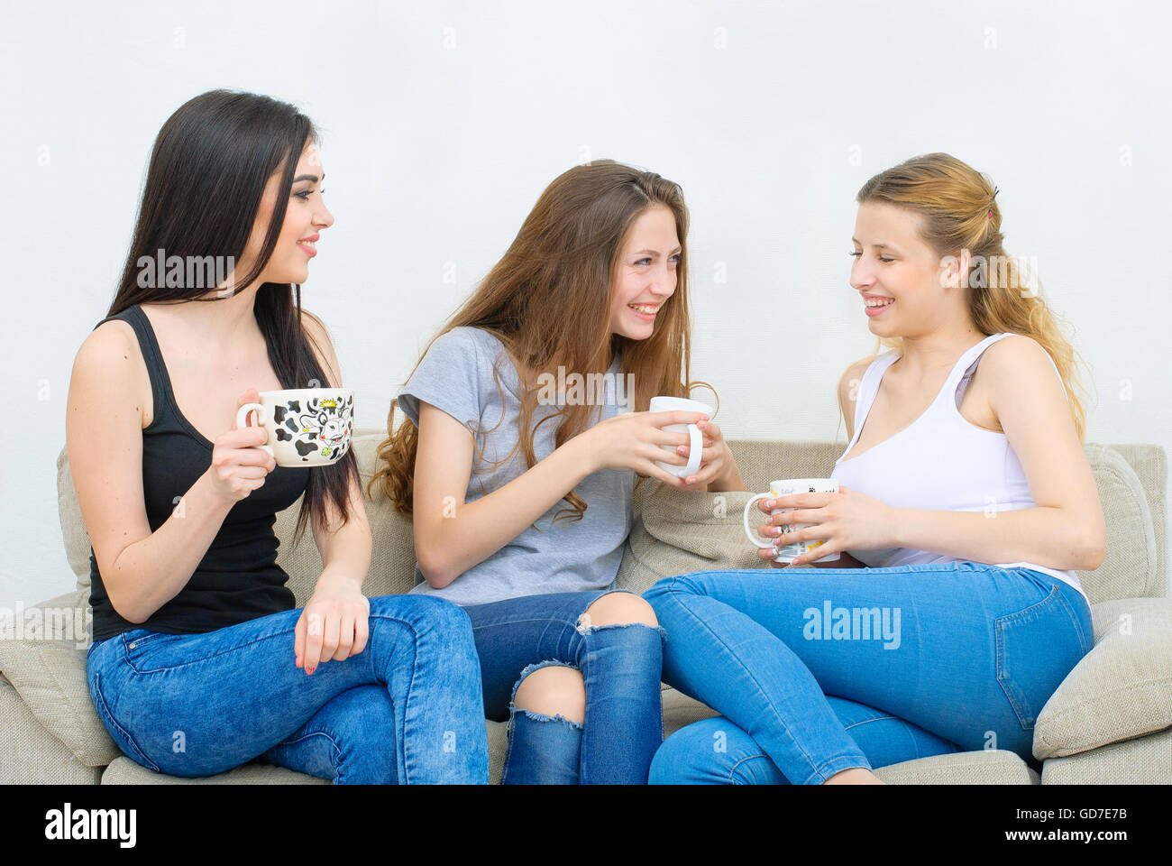 Drei glückliche Freunde reden und trinken Kaffee oder Tee Stockfoto