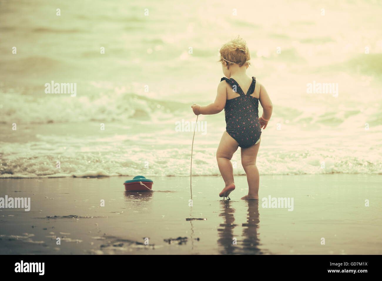 kleines Mädchen am Strand im Meer trägt sie eine bezaubernde Blume-Badeanzug Stockfoto