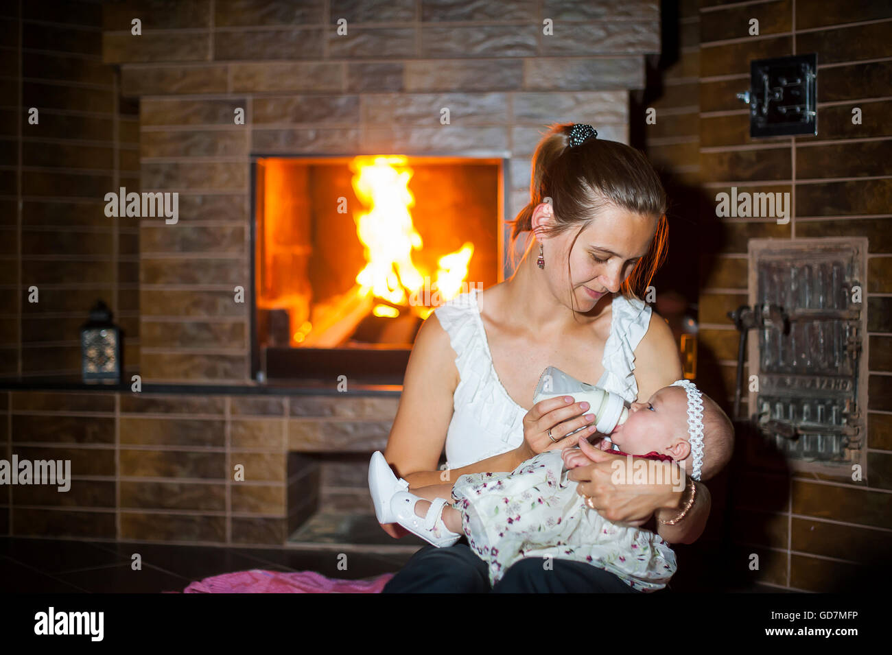 Mutter füttert ihr Baby am Kamin Stockfoto