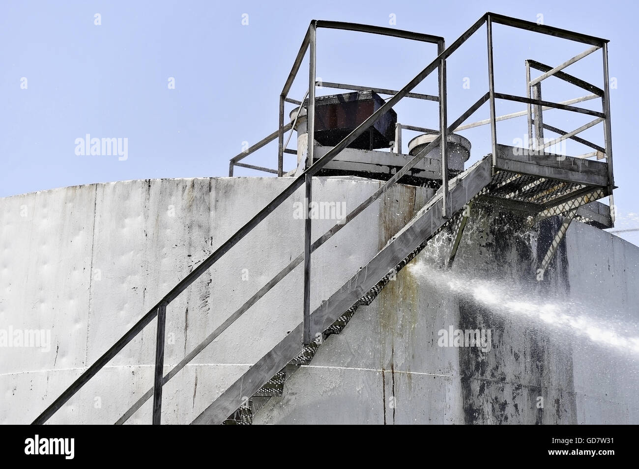 Feuerwehrmann-Wasserstrahl löschen das Feuer in der Nähe von einem Benzin-Lagertank Stockfoto