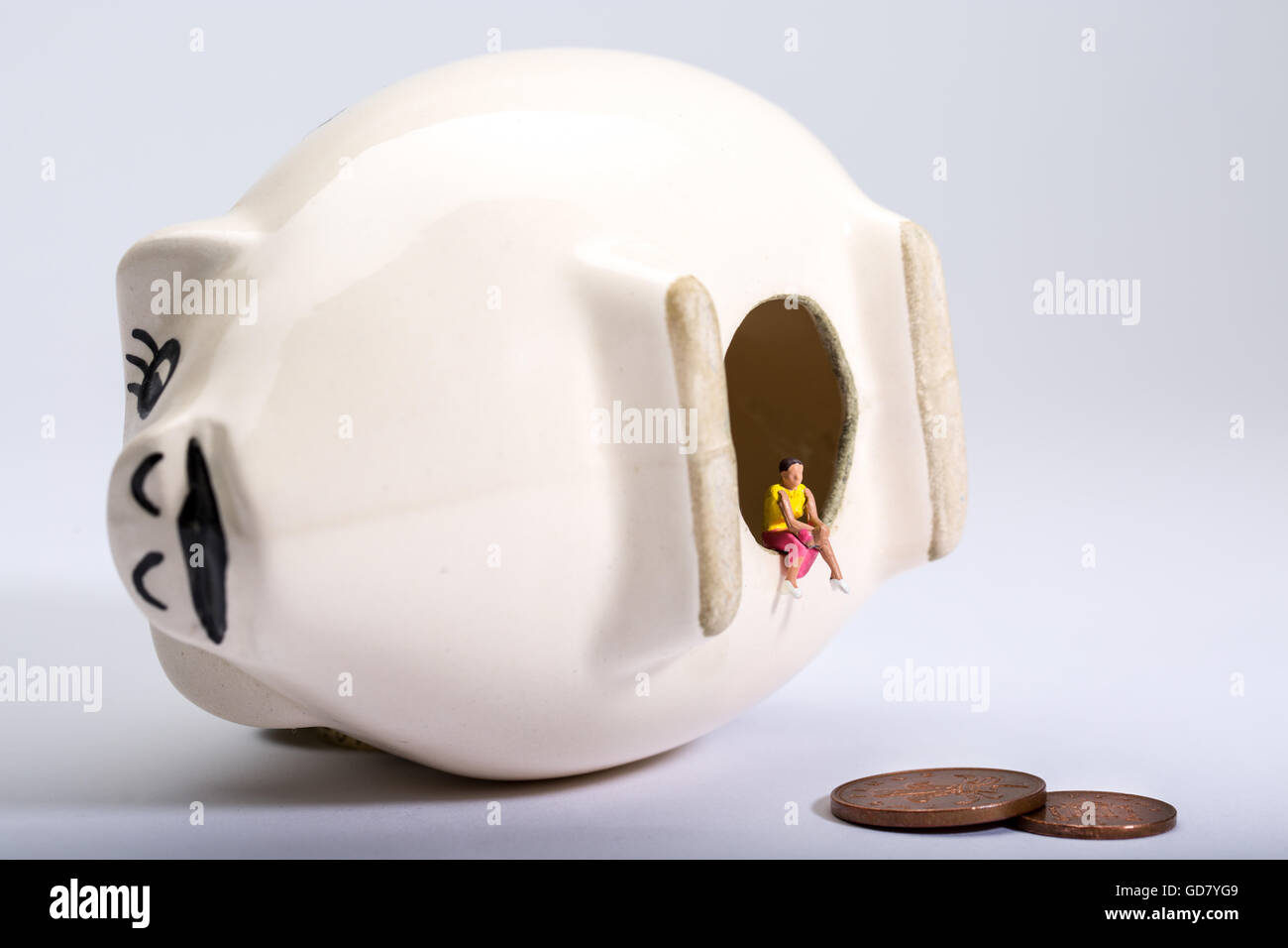 Konzept-Bild der eine einsame Gestalt mit einer leeren Sparschwein zu geringen Einsparungen und niedrige Zinsen auf Spareinlagen zu veranschaulichen Stockfoto