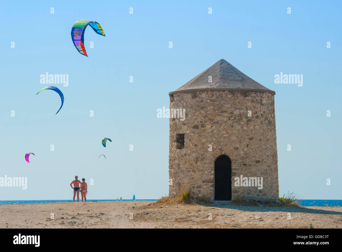 Alte Windmühlen an einem Strand, bevölkert von Windsurfer und Kitesurfer in Lefkada, Lefkas Stockfoto