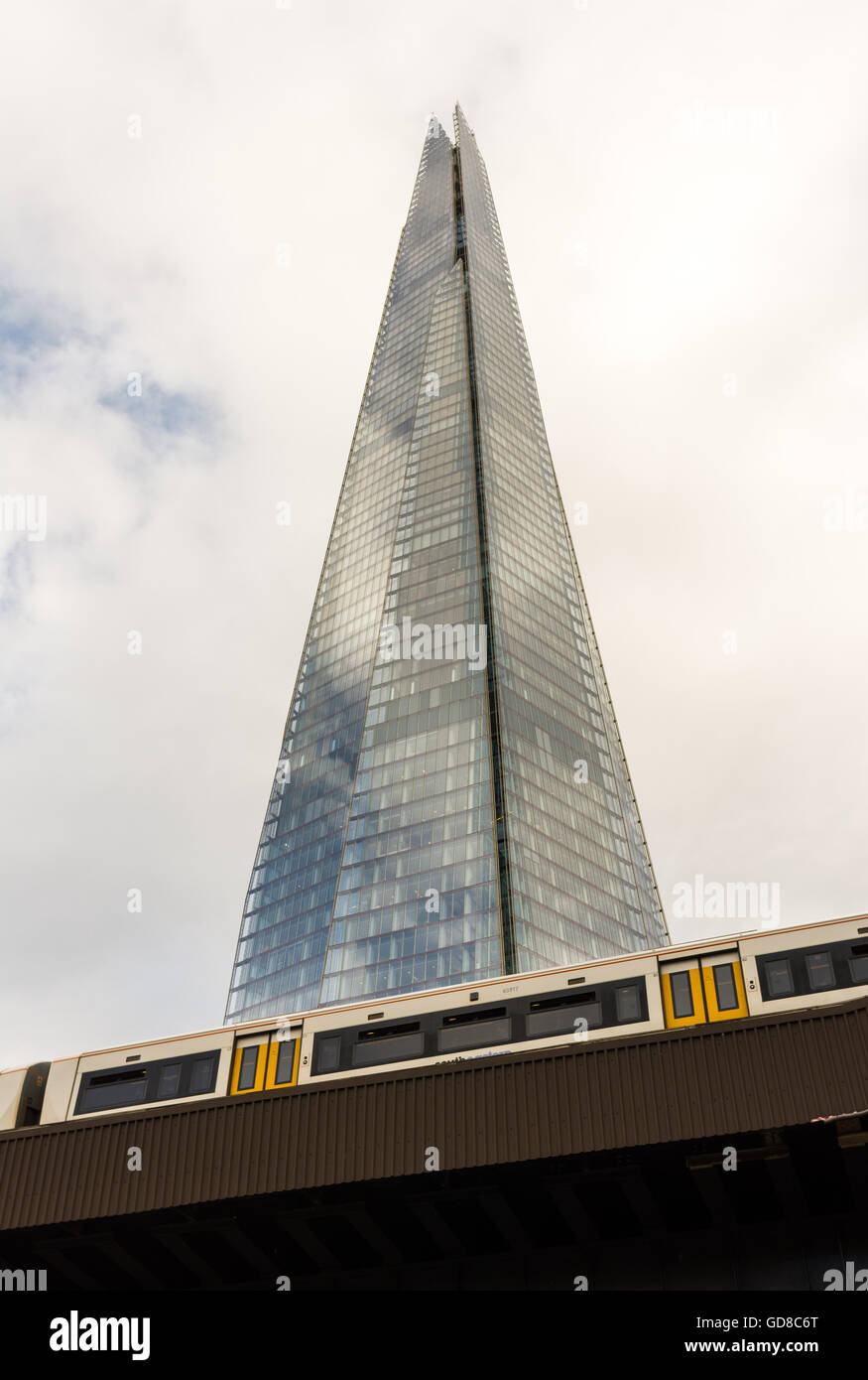 Shard, London, erhebt sich über einem vorbeifahrenden Zug, wie es in London Bridge Station kommt. Stockfoto