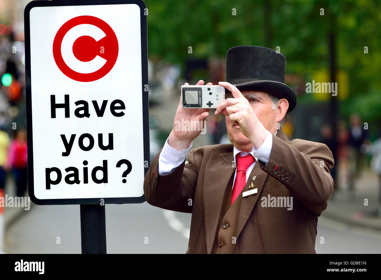 London, England, Vereinigtes Königreich. Hotel-Portier nehmen ein Foto von einer Demonstration in der Park Lane, neben einer City-Maut-Schild Stockfoto