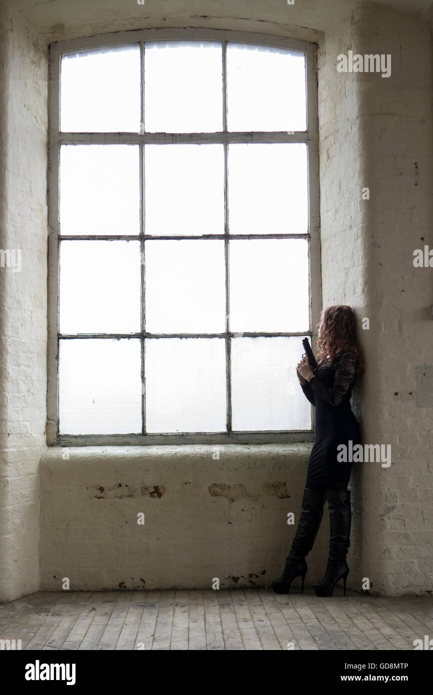 Frau mit einer Pistole am Fenster Stockfoto