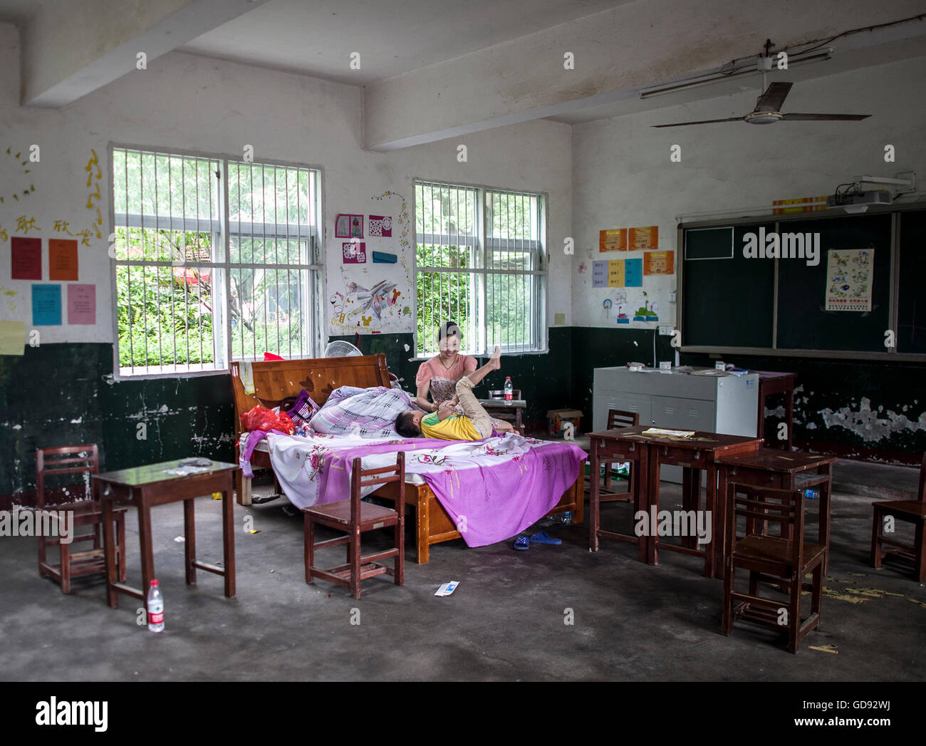 Wuhan. 14. Juli 2016. Dorfbewohner Hu Shengmei spielt (wieder) mit ihrem Sohn in einem behelfsmäßigen Tierheim in Shenghua Grundschule nach der Deich zwischen der Liangzi und Niushan See in Zentral-China Provinz Hubei, 14. Juli 2016 gesprengt wurde. Bewaffnete Polizei zerstört die 3,7 Kilometer langen Damm trennt die Liangzi und Niushan See am Donnerstag zu steigenden Hochwasser zu zerstreuen. Mehr als 1.600 Einwohner, die in der Nähe gelebt haben in behelfsmäßigen Behausungen für weitere Ansiedlungen übertragen. © Xiao Yijiu/Xinhua/Alamy Live-Nachrichten Stockfoto