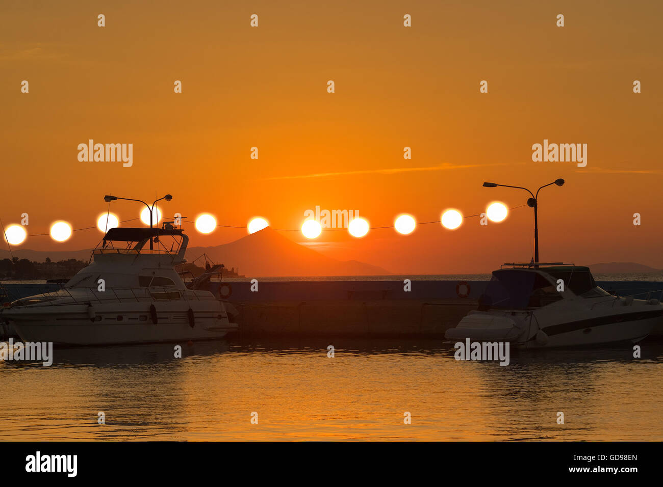 Surrealistische Blick auf einen Sonnenuntergang mit mehreren Sonnen hängen von den Leistungskabeln Strom. Stockfoto