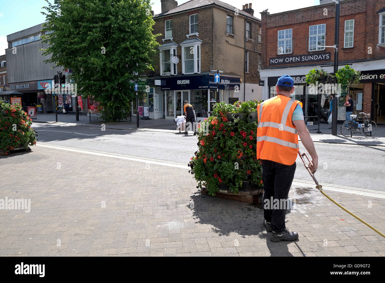 Ein Rat Arbeiter Wasser Blumen auf der High Street Brentwood einer englischen Kleinstadt in Essex Stockfoto