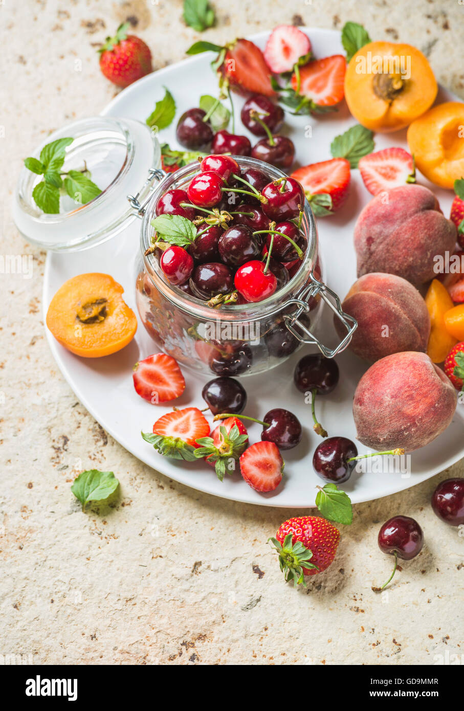 Gesunden Sommer Aromenpalette Sorte. Süße Kirschen, Pfirsiche, Erdbeeren auf weißem Teller über leichte konkreten Hintergrund. Top v Stockfoto