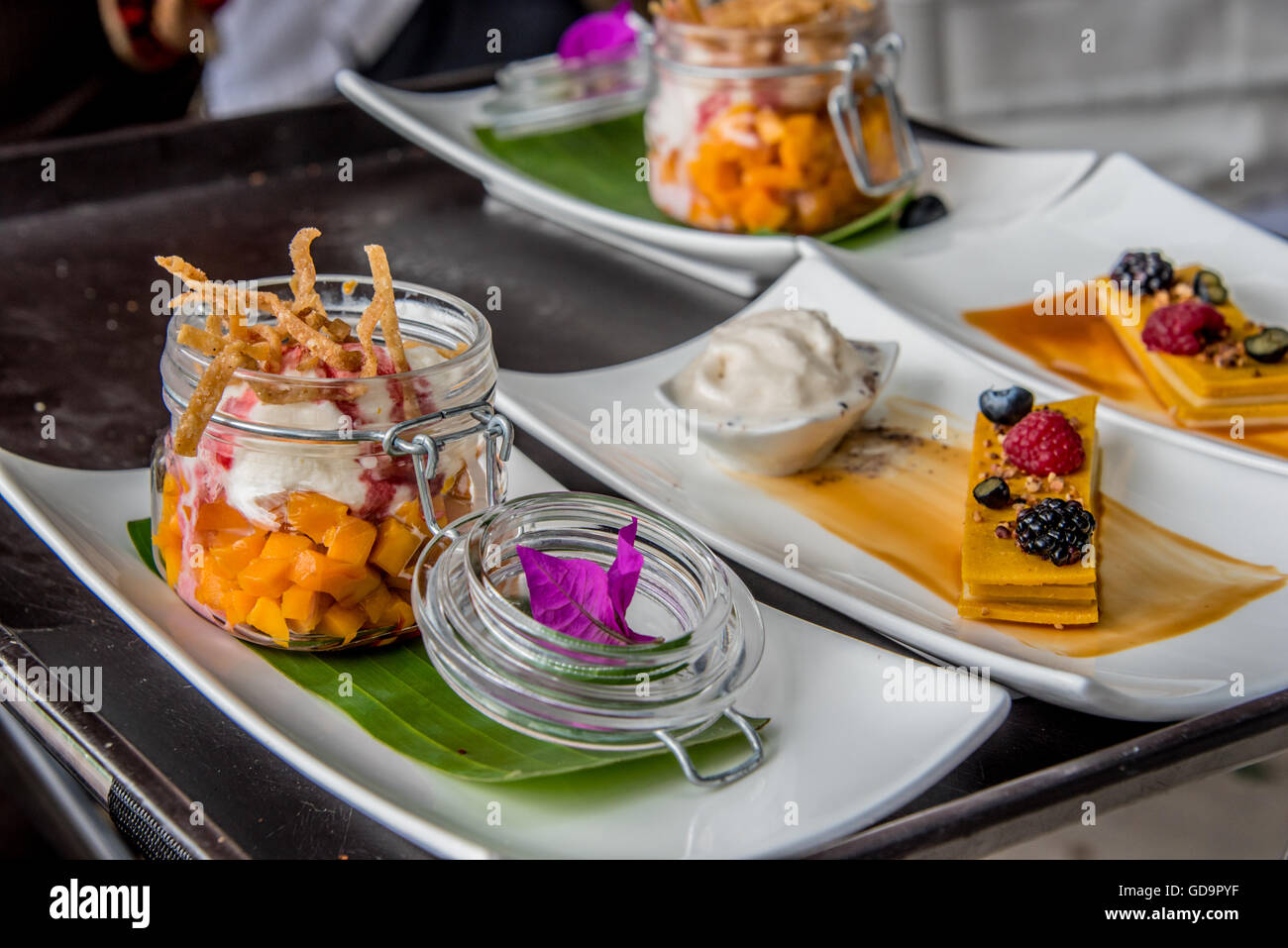 Auswahl an Desserts bei einem Catering Event mit Mango, Churros, Kuchen und Eis mit frischen Früchten garniert Stockfoto