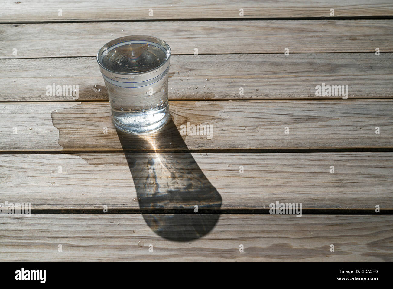 Glas Wasser auf Holz Hintergrund, um die Sonne. Verschüttetes Wasser. Textfreiraum Stockfoto
