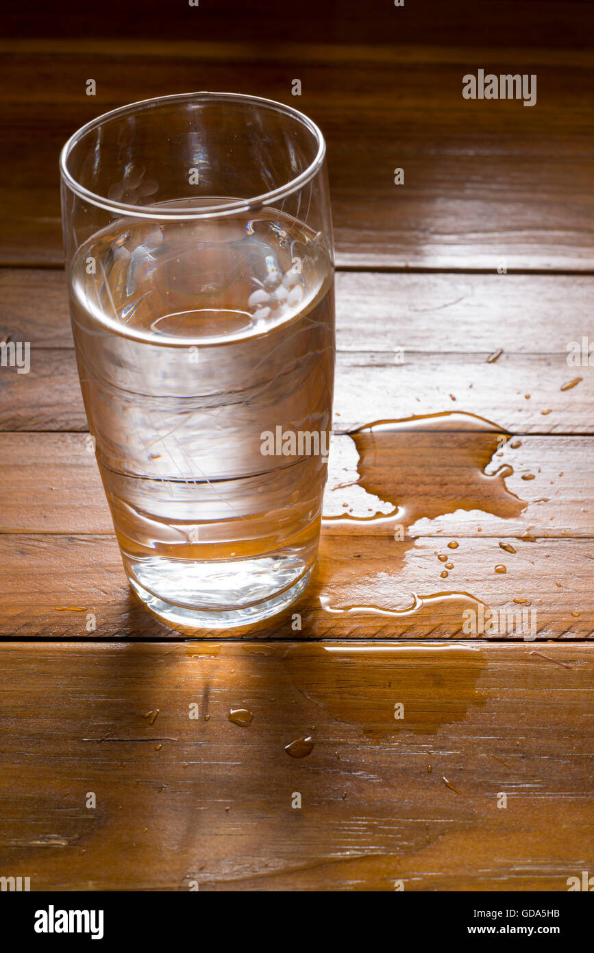 Glas Wasser auf Holz Hintergrund.  Verschüttetes Wasser Stockfoto
