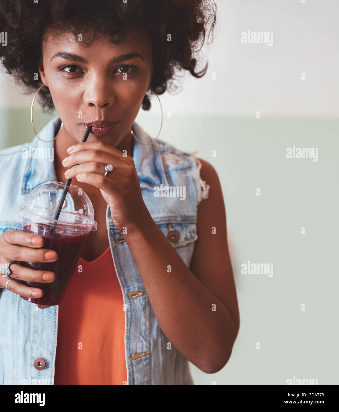 Nahaufnahme Bild von einer attraktiven jungen Frau Saft zu trinken. Stilvolle afrikanische weibliche Modell immer eine Erfrischung. Stockfoto